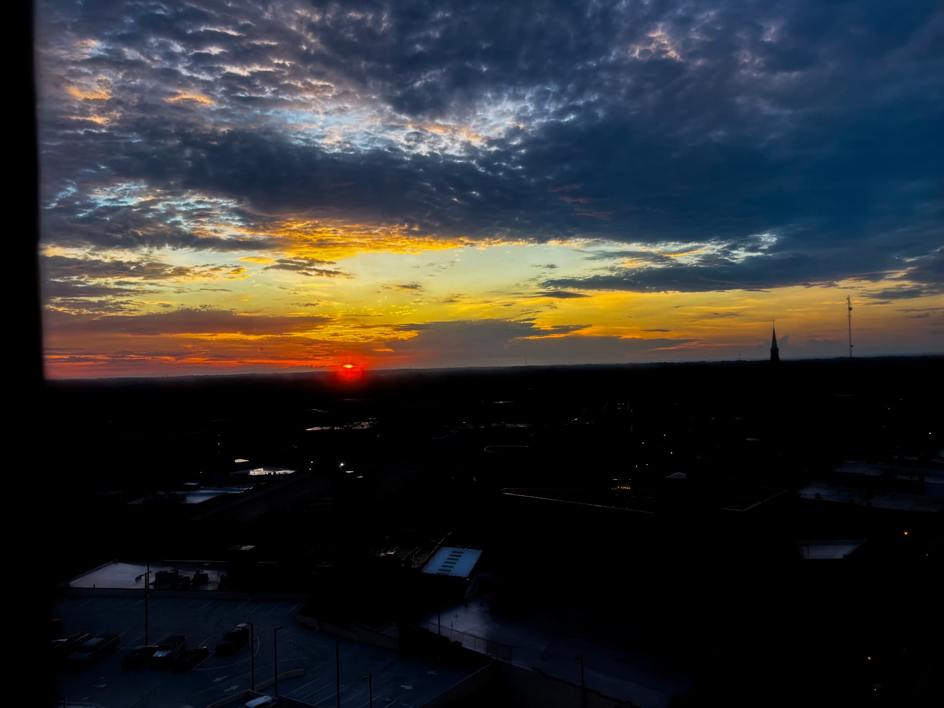 Last sliver of red sun on the horizon seen from a high window