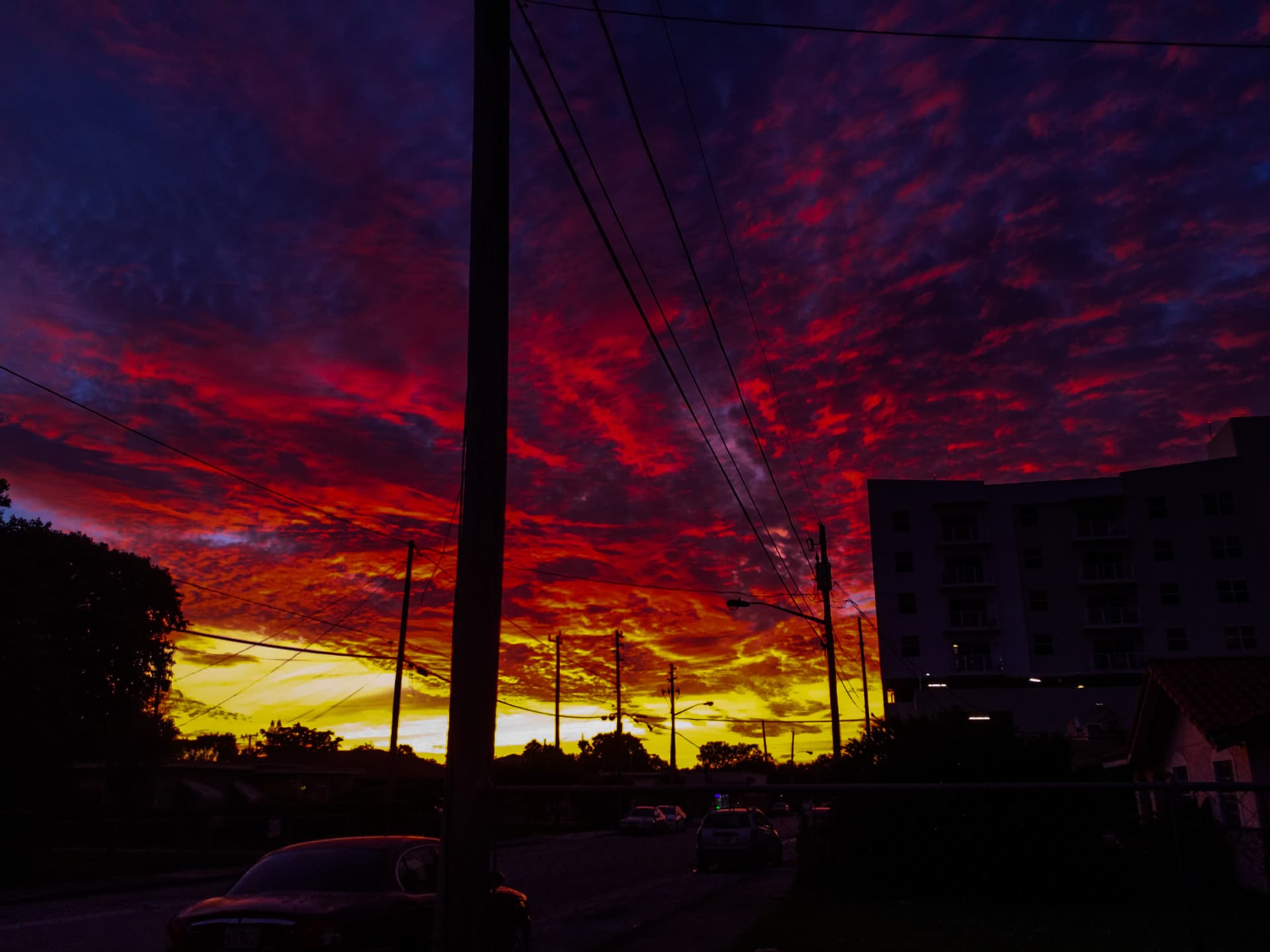 Fiery red, purple, and gold sunset over a city street