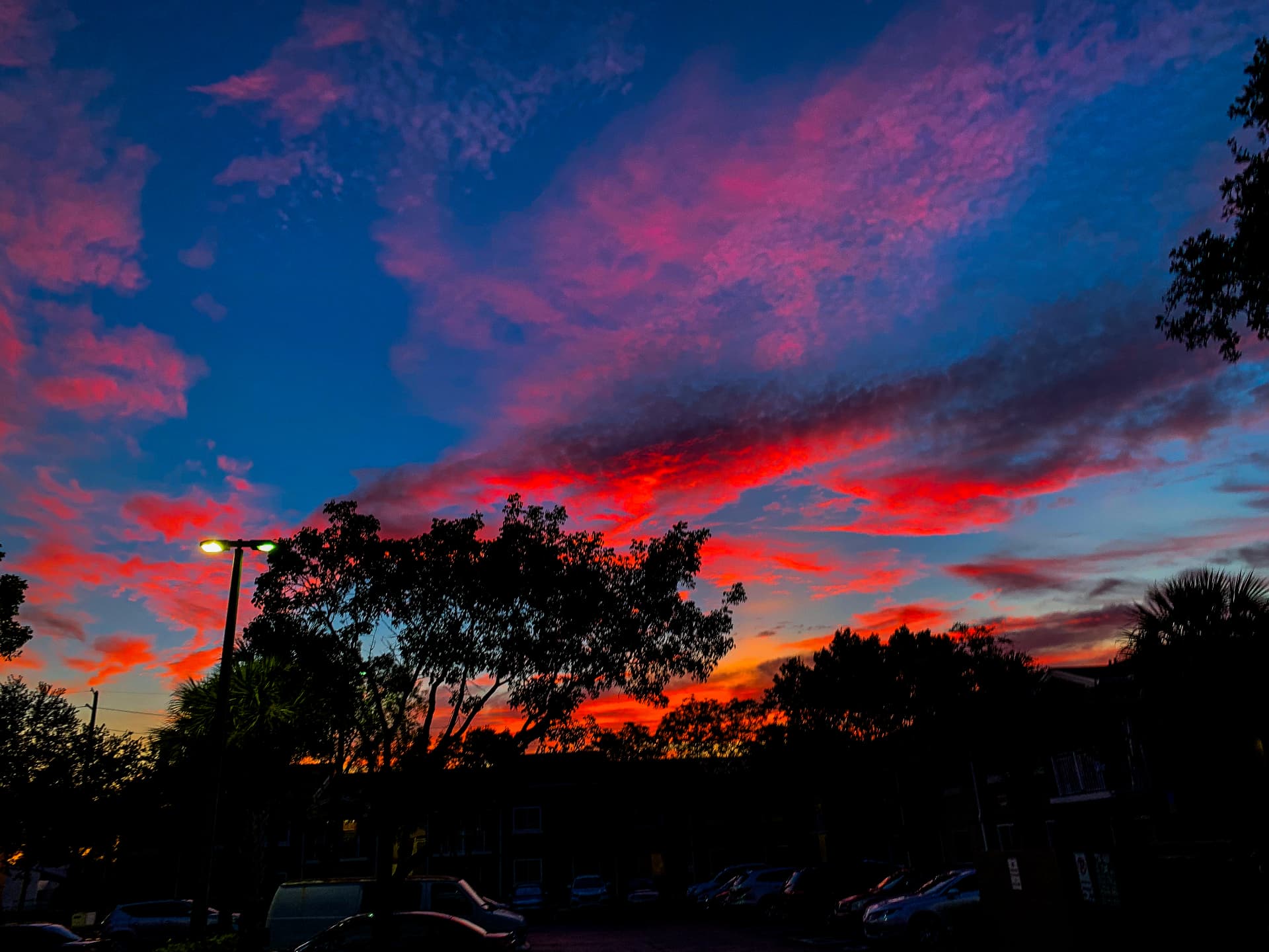 Deep blue sky with crimson clouds over a parking lot at dusk
